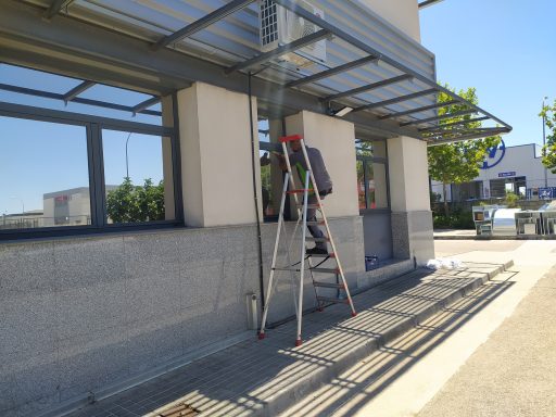 Un técnico de LTC en una escalera, aplicando láminas de protección solar a la ventana